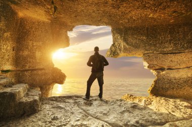 Adam gün batımında mağarada duruyor. İnsanlar maceralı kavramsal sahneler ile seyahat ederler. İzole nesne. 