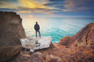 Adam uçurumun kenarında duruyor ve denizde görünüyor. Adam sakin ol doğa üzerinde.