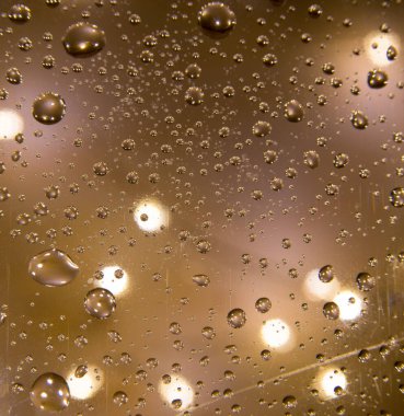 Defocus, pencereye gece yağmuru damlaları, arka plan lambaların Noel ışıklarını yıkadı.