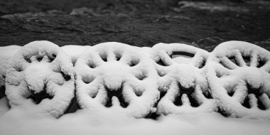 Snow covered cart wheels at a river background. Monochrome image. Selective focus.