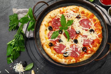 Freshly baked pepperoni pizza on dark background. Tasty homemade food concept. Top view, copy space