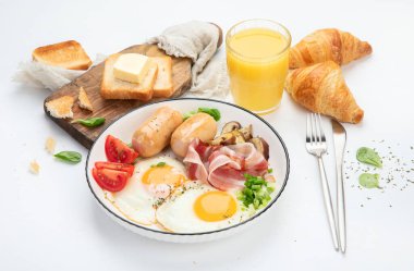 İngiliz kahvaltısı, kızarmış yumurta, sosis, pastırma ve beyaz arka planda tost. 