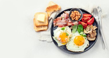 Full English breakfast with fried egg, sausage, bacon and toast on grey background. Top view, copy space clipart