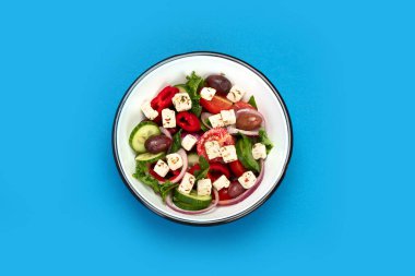 Greek salad on color background. Traditional food. Creative photo concept. Top view, copy space clipart