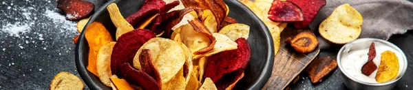 Bowl of healthy colorful vegetable chips on dark background,  panorama, banner