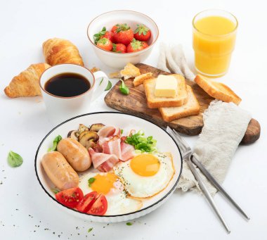 İngiliz kahvaltısı, kızarmış yumurta, sosis, pastırma ve beyaz arka planda tost. 