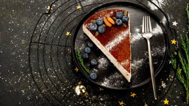 Karanlık arka planda noel pastası dilimi. Bayram zamanının geleneksel tatlısı. Üst görünüm, alanı kopyala