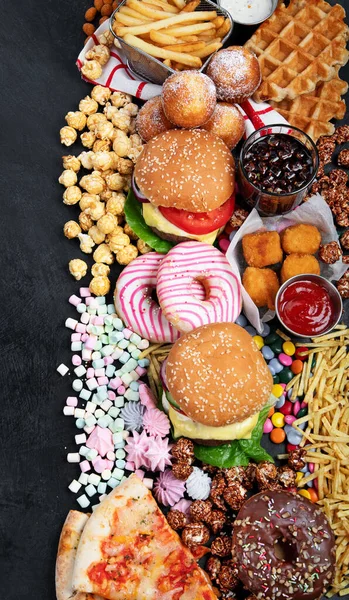 Unhealthy products. food bad for figure, skin, heart and teeth. Assortment of fast carbohydrates food with fries and cola on a dark background. Top view.