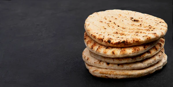 Pita bread isolated on a dark background. Traditional and typical food of Arabic cuisine. Top view. Panorama.