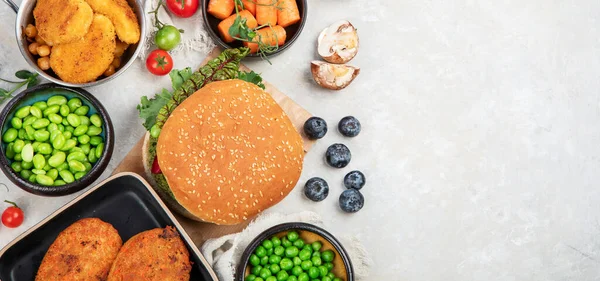 Plant-based food concept-vegan burgers, sausages, vegetarian nuggets, fresh vegetables and sauces on a white background. Top view. Panorama with copy space.