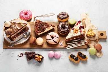 Ahşap bir masa üzerinde çeşitli pasta parçaları, kurabiyeler, kurabiyeler ve çörekler. Üst Manzara. Şekerleme arkaplanı.