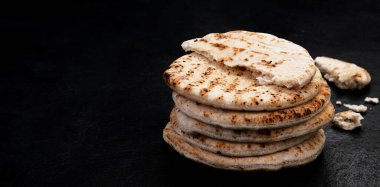 Koyu bir arka planda izole edilmiş Pita ekmeği. Geleneksel ve tipik Arap yemekleri. Üst Manzara. Panorama.