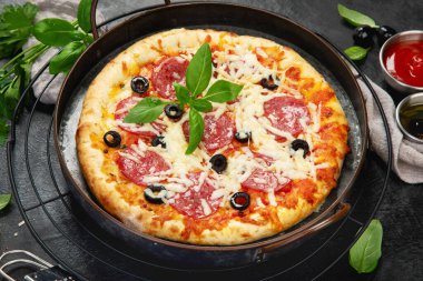 Freshly baked pepperoni pizza on dark background. Tasty homemade food concept. 