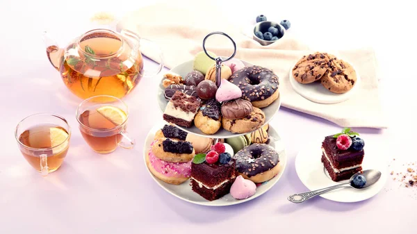 Traditional English tea. Afternoon tea with  selection of sweets  on violet background. Holiday concept