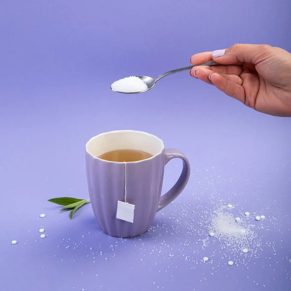 和糖一起吃来一杯茶紫罗兰色背景下的人造糖 顶部视图 — 图库照片