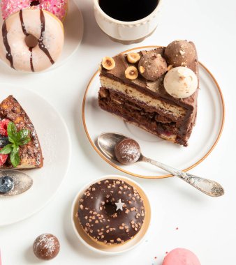 Üzerinde çeşitli kurabiyeler, çörekler, kekler, peynirli kekler ve beyaz arka planda kahve fincanları olan masa. Lezzetli tatlı masası. Üst manzara, düz uzanma