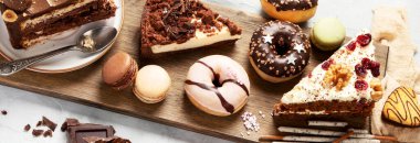 Ahşap bir masa üzerinde çeşitli pasta parçaları, kurabiyeler, kurabiyeler ve çörekler. Üst Manzara. Şekerleme arka planı. Panorama.