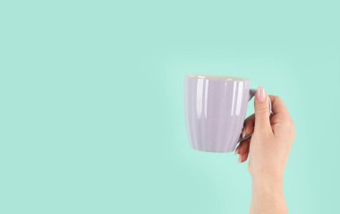 Yeşil arka planda çay fincanı tutan kollar havada. Kavramsal fotoğraf. Ön görünüm, boşluğu kopyala