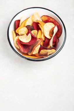 Beyaz arka planda izole edilmiş bir kase sağlıklı sebze cipsi. Üst görünüm.