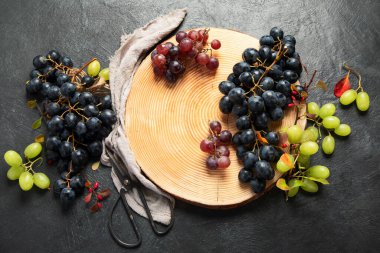Tahta bir tabakta yeşil ve siyah üzümler. Üst görünüm.
