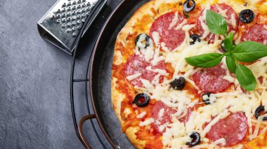 Freshly baked pepperoni pizza on dark background. Tasty homemade food concept. Top view, copy space