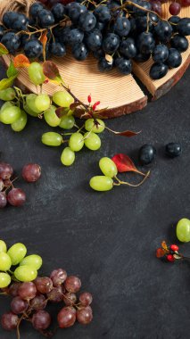 Tahta bir tabakta yeşil ve siyah üzümler. Üst görünüm.