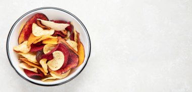 Beyaz arka planda izole edilmiş bir kase sağlıklı sebze cipsi. Üst Manzara. Kopyalama alanı olan Panorama.