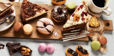 Ahşap bir masa üzerinde çeşitli pasta parçaları, kurabiyeler, kurabiyeler ve çörekler. Üst Manzara. Şekerleme arkaplanı.