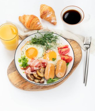 İngiliz kahvaltısı, kızarmış yumurta, sosis, pastırma ve beyaz arka planda tost. 