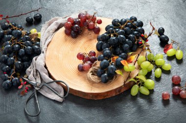 Tahta bir tabakta yeşil ve siyah üzümler. Üst görünüm.