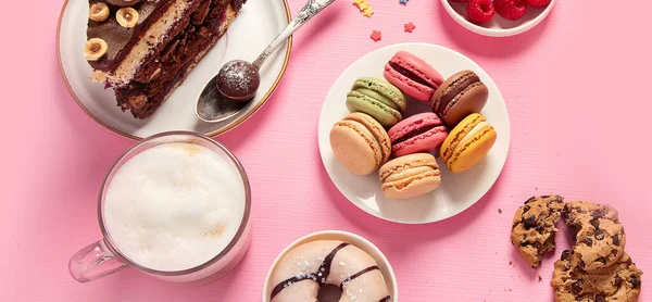 Çeşitli kurabiyeler, çörekler, kekler, peynirli kekler ve pembe arka planda kahve fincanları. Lezzetli tatlı masası. Üst manzara, düz yatak, panorama, pankart