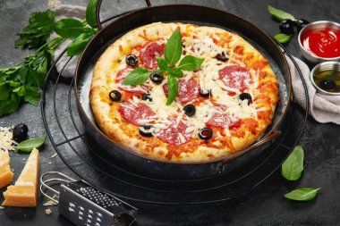 Freshly baked pepperoni pizza on dark background. Tasty homemade food concept. 