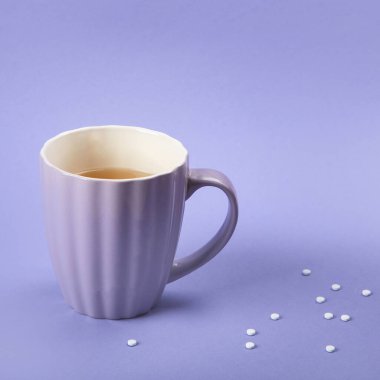 Tatlandırıcılı bir fincan çay. Menekşe arkaplanda suni şeker, üst görünüm.