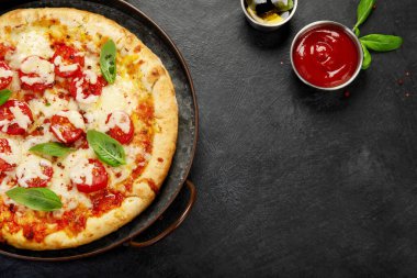 Freshly baked pizza on dark background. Tasty homemade food concept. Top view, copy space