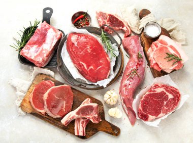 Çeşitli taze et türleri: gri arka planda domuz eti, sığır eti ve tavuk. Üst görünüm.