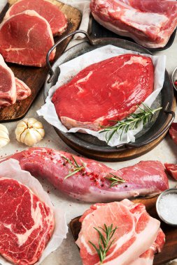 Çeşitli taze et türleri: gri arka planda domuz eti, sığır eti ve tavuk. Üst görünüm.