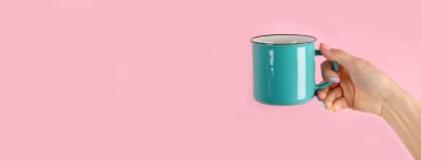 Kollarını kaldır ve pembe arka planda kahve fincanı tut. Kavramsal fotoğraf. Ön manzara, panorama