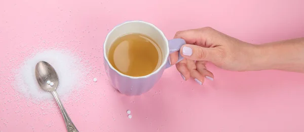 Cup of tea with sugar substitute on pink background. Healthy hot beverage. Top view, flat lay, copy space