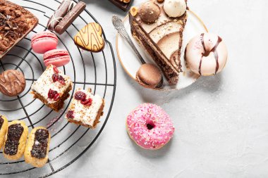 Arka planda çeşitli kurabiyeler, çörekler, kekler ve kahve fincanları olan masa. Üst görünüm.