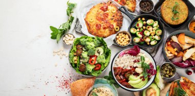 Gri masada vejetaryen ve çeşitli vejetaryen yemekleri. Vitaminli, lifli ve antioksidanlı sağlıklı gıda konsepti. Üst Manzara. Kopyalama alanı olan Panorama.