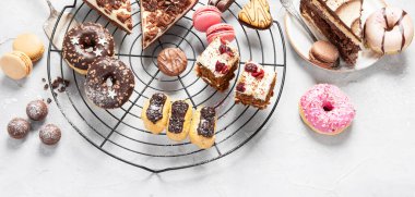 Arka planda çeşitli kurabiyeler, çörekler, kekler ve kahve fincanları olan masa. Üst Manzara. Panorama.