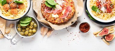 Tabaklar dolusu İtalyan yemeği, pizza, makarna, köfte, salam, parmesan, zeytin, beyaz arka planda ekmek çubukları. Üst Manzara. Kopyalama alanı olan Panorama.