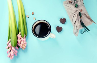 Morning cup of coffee, candy, gift or present box and pink spring flowers on blue background. Breakfast for Birthday, Holiday, Women day, Mother day,. Zero waste Valentine's Day concept