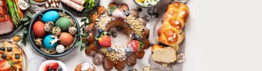 Traditional Easter dinner or  brunch with ham, colored eggs, hot cross buns, cake and vegetables. Easter meal dishes with holday decorations. Top view, copy space, panorama, banner