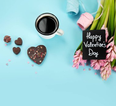 Morning cup of coffee, candy, gift or present box and pink spring flowers on blue background. Breakfast for Birthday, Holiday, Women day, Mother day,. Zero waste Valentine's Day concept