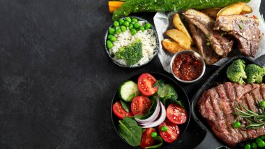 Çeşitli sağlıklı pişmiş et çeşitleri - sığır eti, domuz eti, sebze ve salatalı koyu bir arka planda tavuk. Üst görünüm.