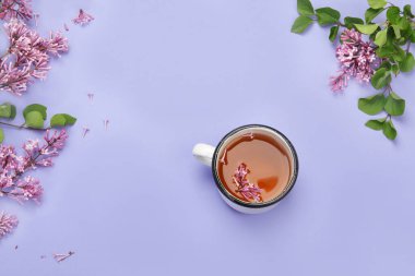 Renkli arka planda bir fincan çayla leylak çiçekleri. Atmosfer yaz konsepti. Üst görünüm, düz görünüm, kopyalama alanı