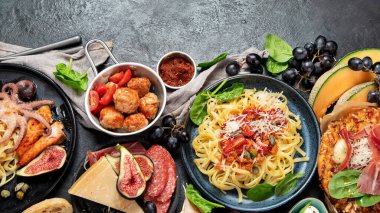 Dinner table of italian meals dishes.  Pizza, pasta, antipasto  on black background. Healthy eating concept. Top view