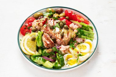 Tuna salad with boiled egg, tomato, lettuce, cucumber and red onion. Healthy and detox food concept. Ketogenic diet. Fresh vegetable salad bowl on white background. Top view.