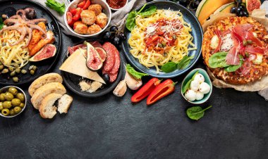 Dinner table of italian meals dishes.  Pizza, pasta, antipasto  on black background. Healthy eating concept. Top view, copy space